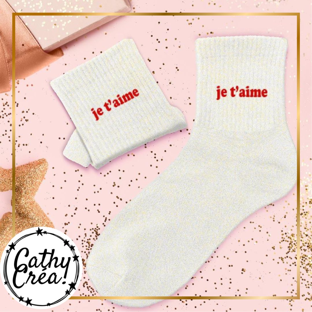 Chaussettes je t'aime blanc et or posées dans décor cadeau confettis dorés et étoiles