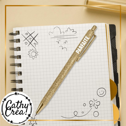 Stylo à paillettes dorées Parfaite posé sur un carnet de notes